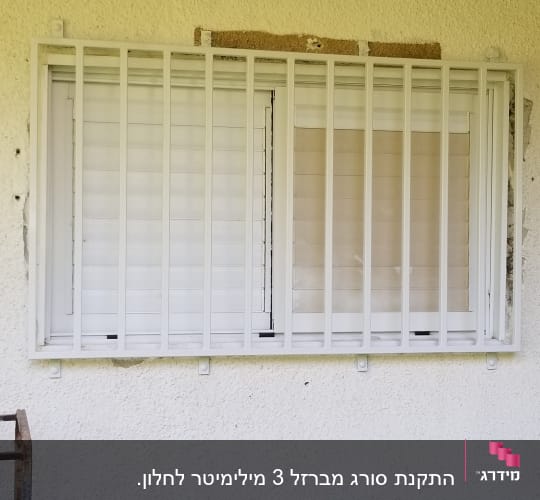 חלון עם סורגים לבנים על קיר חיצוני